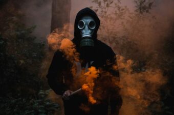 a person wearing a gas mask holding a stick with orange smoke