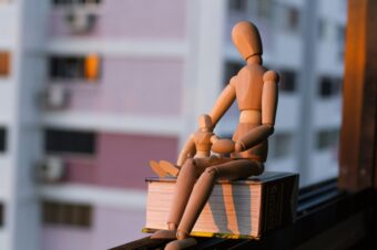 an adult and child sized wooden model sitting on top of a book
