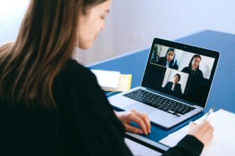 A candidate participates in a virtual interview via a laptop, engaging with multiple interviewers in a professional setting