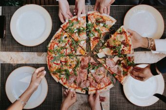many hands taking a slice of an artisan pizza