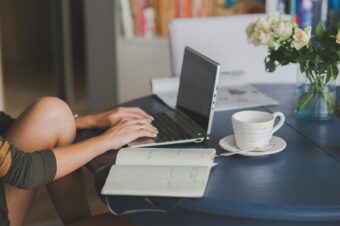 A person working on a laptop at a tidy table with a notebook and coffee, symbolizing effective time management for software developers.