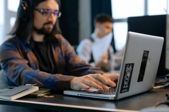 software developer typing on his laptop with his hands in focus