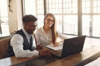 two people discussing and smiling in front of a laptop