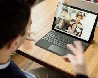 A person participates in a virtual team meeting using a laptop, symbolizing efforts to build trust in remote teams.