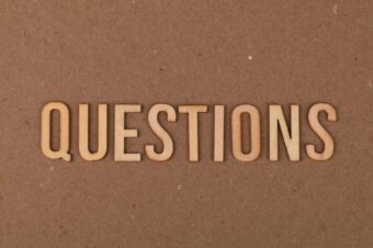 Wooden letters spelling the word "QUESTIONS" on a brown background, symbolizing interview questions to ask the panel.